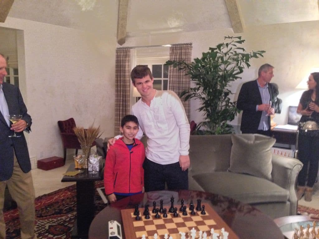 A young Soham Jinsi standing with World Chess Champion Magnus Carlsen next to a chess set